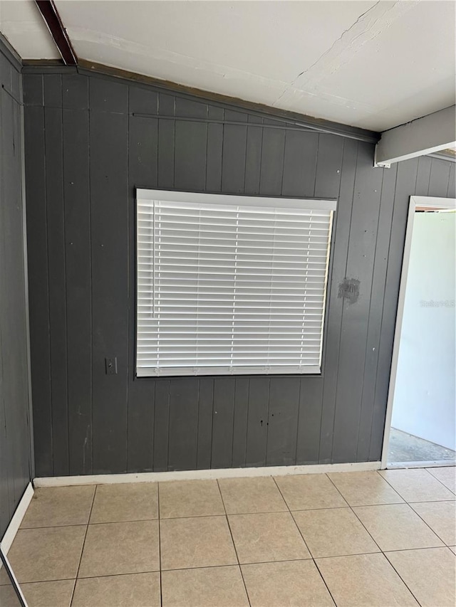 tiled spare room with beam ceiling