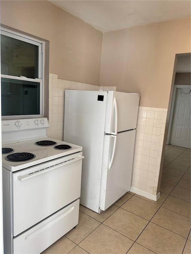 kitchen with white appliances, tile walls, and light tile patterned floors