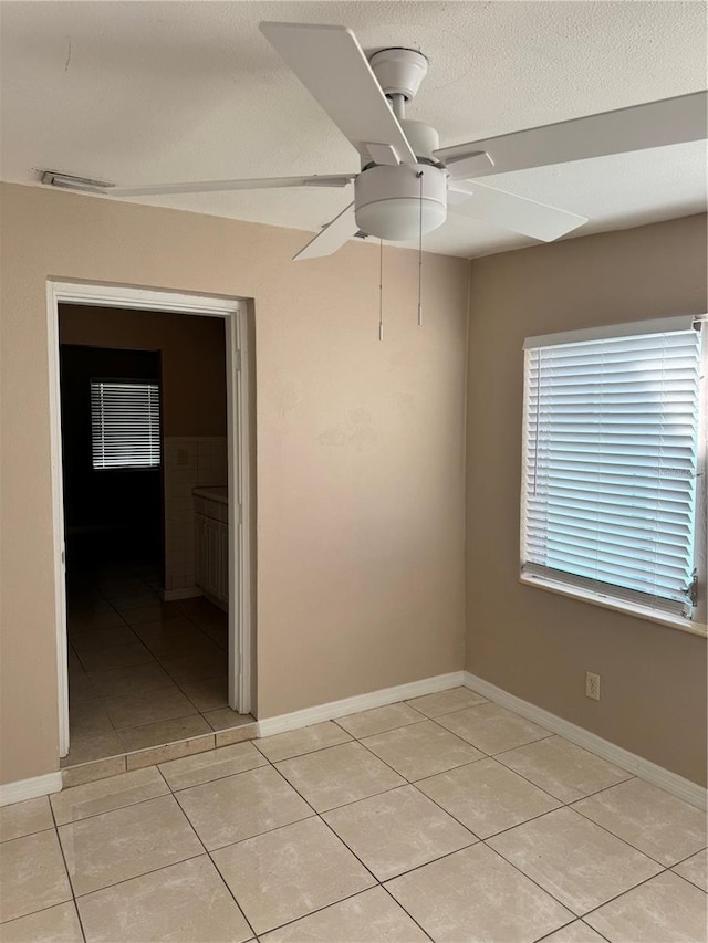 unfurnished room featuring light tile patterned flooring, a textured ceiling, and ceiling fan