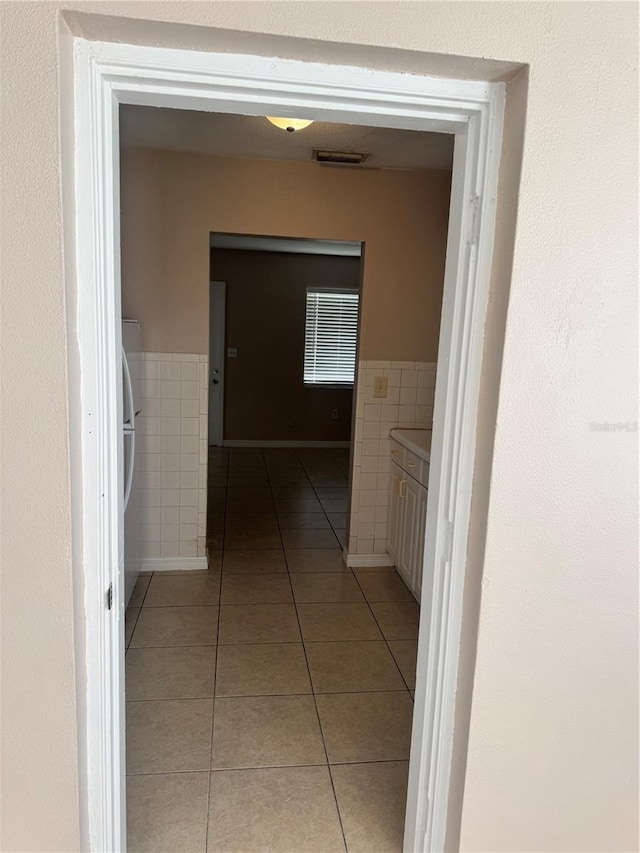 corridor with tile walls and light tile patterned floors