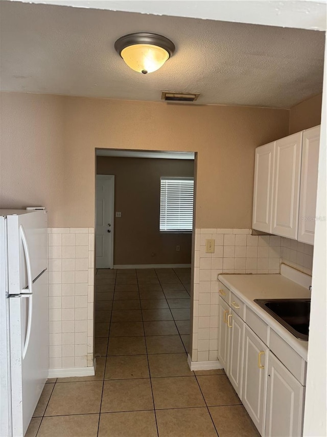 kitchen with sink, light tile patterned floors, white cabinets, and white fridge