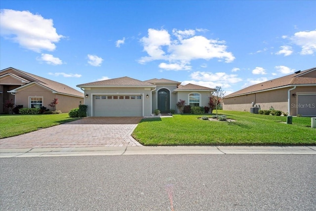 view of front of property featuring an attached garage, a front lawn, decorative driveway, and stucco siding