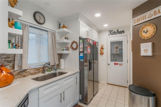 kitchen with tasteful backsplash, light stone countertops, sink, white cabinetry, and stainless steel fridge with ice dispenser