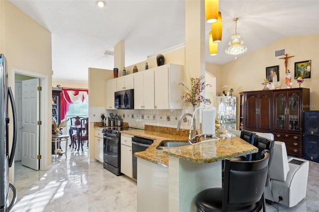 kitchen with lofted ceiling, decorative light fixtures, black appliances, kitchen peninsula, and a breakfast bar area