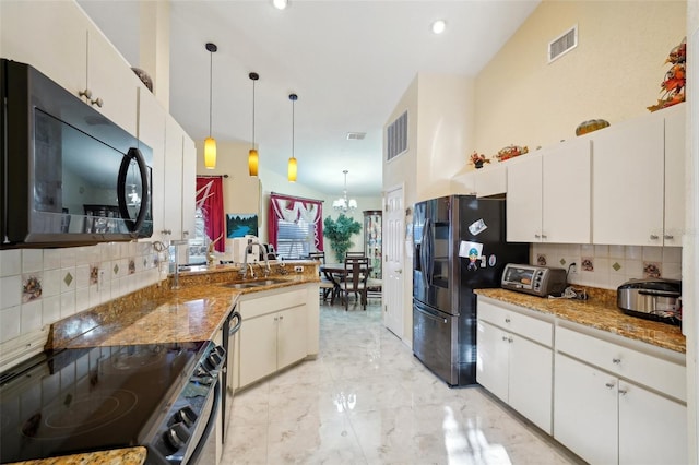 kitchen featuring dark stone countertops, sink, white cabinetry, stainless steel appliances, and hanging light fixtures