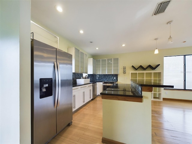1793 N Fort Harrison Ave, Clearwater, FL 33755 - kitchen featuring appliances with stainless steel finishes, pendant lighting, white cabinets, decorative backsplash, and light hardwood / wood-style flooring