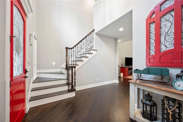 entrance foyer with dark hardwood / wood-style flooring and a towering ceiling