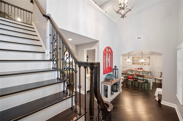 staircase featuring a high ceiling, hardwood / wood-style floors, and a notable chandelier