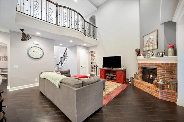 living room with a brick fireplace, a high ceiling, and dark hardwood / wood-style floors