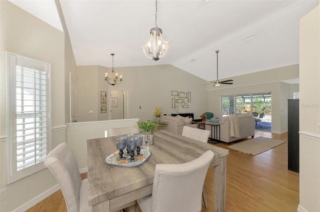 dining space featuring lofted ceiling, light hardwood / wood-style floors, and ceiling fan with notable chandelier