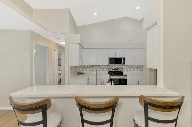 kitchen with appliances with stainless steel finishes, decorative backsplash, white cabinetry, and kitchen peninsula