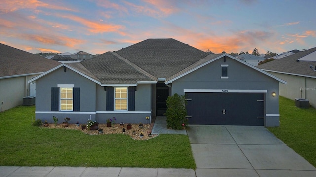 single story home featuring a yard, stucco siding, concrete driveway, an attached garage, and cooling unit