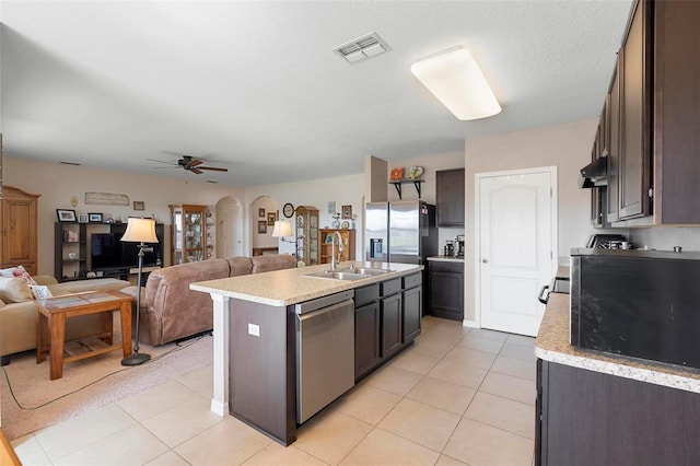 kitchen with stainless steel appliances, arched walkways, light countertops, and a sink