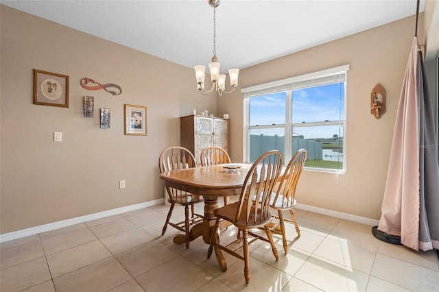 dining room with a chandelier, light tile patterned floors, and baseboards