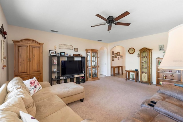 living room with arched walkways, light carpet, visible vents, and a ceiling fan