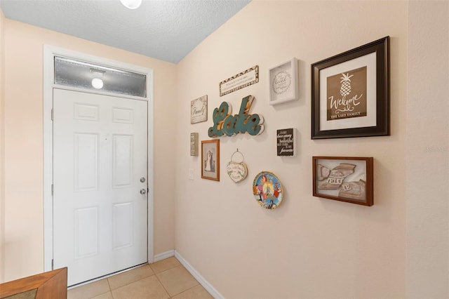 entryway featuring light tile patterned floors, baseboards, and a textured ceiling