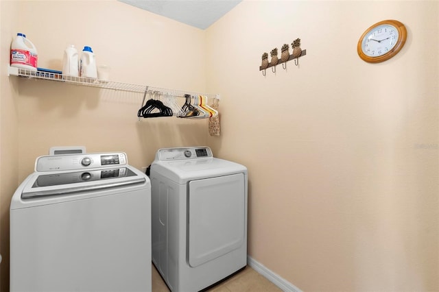 laundry room with laundry area, light tile patterned floors, baseboards, and washer and clothes dryer