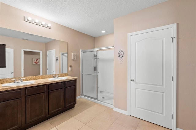 full bathroom featuring a stall shower, tile patterned flooring, a sink, and double vanity