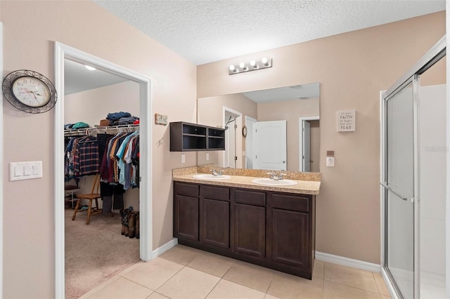 bathroom with a stall shower, tile patterned floors, a sink, and double vanity