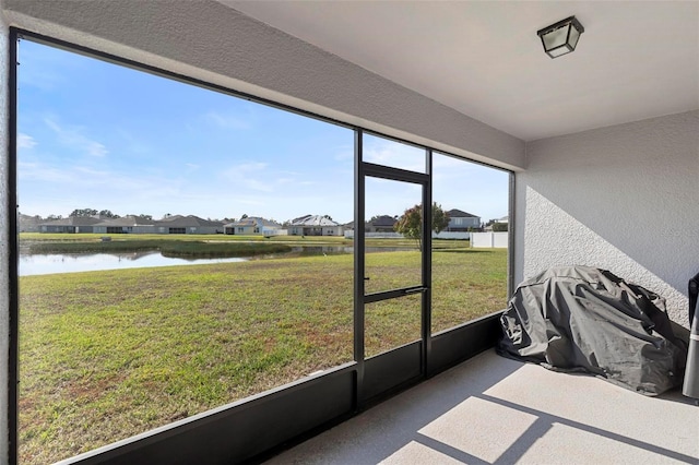 unfurnished sunroom with a water view, a residential view, and a wealth of natural light