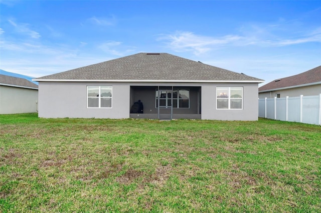 back of house featuring a shingled roof, stucco siding, a lawn, and fence