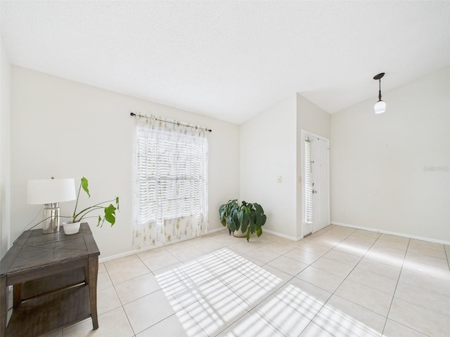 interior space with lofted ceiling, a textured ceiling, baseboards, and tile patterned floors