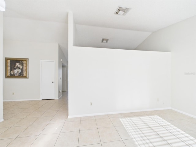 spare room with lofted ceiling, visible vents, baseboards, and light tile patterned floors