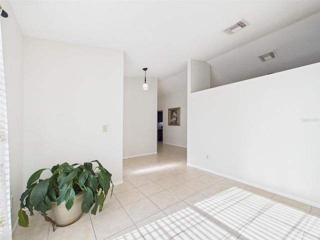 spare room with light tile patterned floors, vaulted ceiling, visible vents, and baseboards