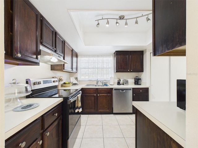 kitchen with stainless steel appliances, a raised ceiling, light countertops, a sink, and under cabinet range hood