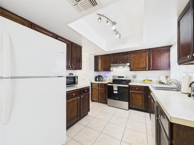 kitchen with under cabinet range hood, stainless steel appliances, a sink, light countertops, and a raised ceiling