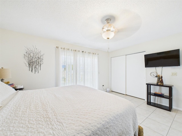 bedroom with light tile patterned floors, a closet, a textured ceiling, and a ceiling fan