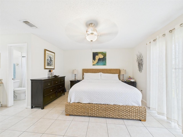 bedroom with light tile patterned floors, a textured ceiling, visible vents, and ensuite bathroom