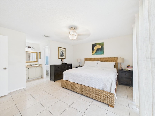 bedroom with light tile patterned floors, visible vents, a ceiling fan, ensuite bath, and a textured ceiling