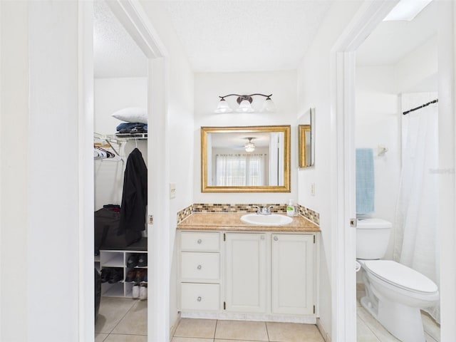 bathroom featuring a textured ceiling, tile patterned flooring, toilet, and a walk in closet