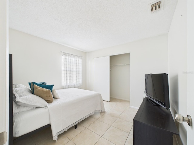 bedroom with a textured ceiling, a closet, light tile patterned flooring, and visible vents