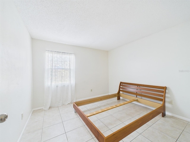 tiled bedroom featuring a textured ceiling and baseboards