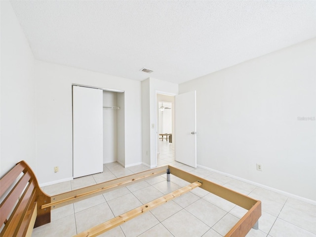 unfurnished bedroom featuring visible vents, a textured ceiling, baseboards, and tile patterned floors