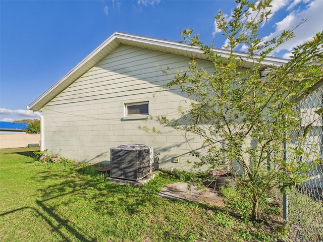 view of side of property featuring cooling unit and a lawn