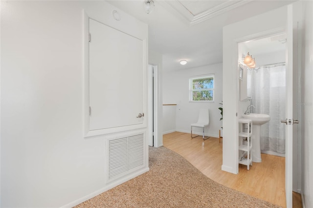 hallway featuring visible vents, light wood-style flooring, and baseboards