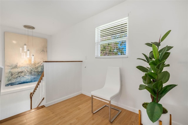 living area with light wood-style floors, baseboards, and an upstairs landing