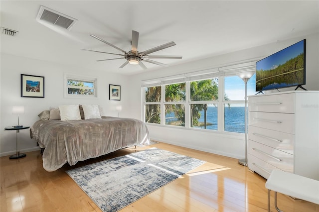 bedroom with light wood finished floors, visible vents, and baseboards