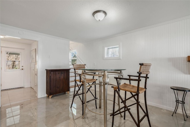 dining space featuring crown molding and baseboards