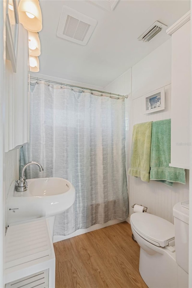 full bath featuring toilet, a shower with curtain, visible vents, and wood finished floors