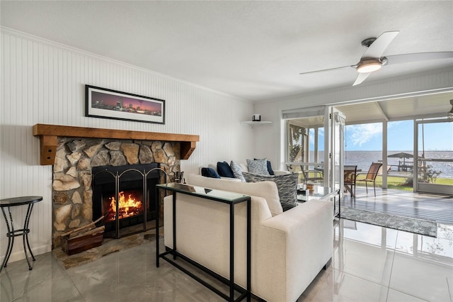 living room featuring a stone fireplace, crown molding, and ceiling fan
