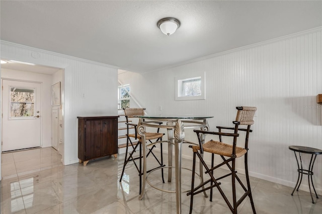 dining room featuring a bar, baseboards, and ornamental molding