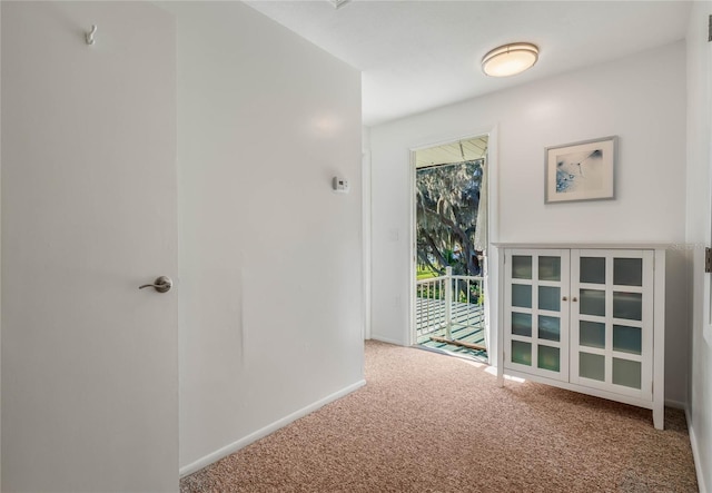 corridor featuring baseboards and carpet flooring