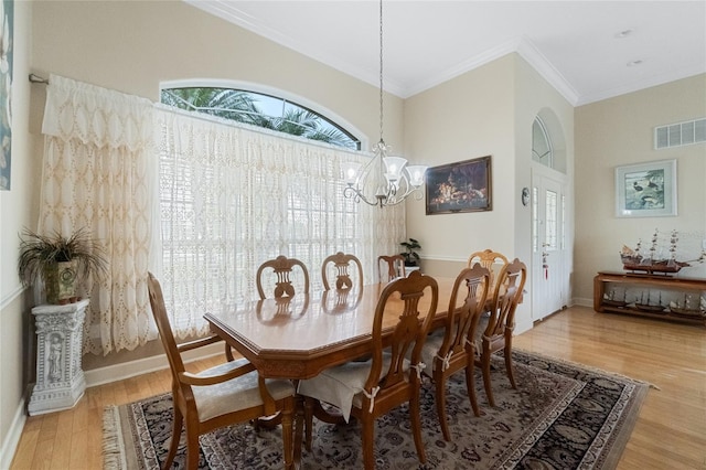 dining space with visible vents, an inviting chandelier, ornamental molding, wood finished floors, and baseboards