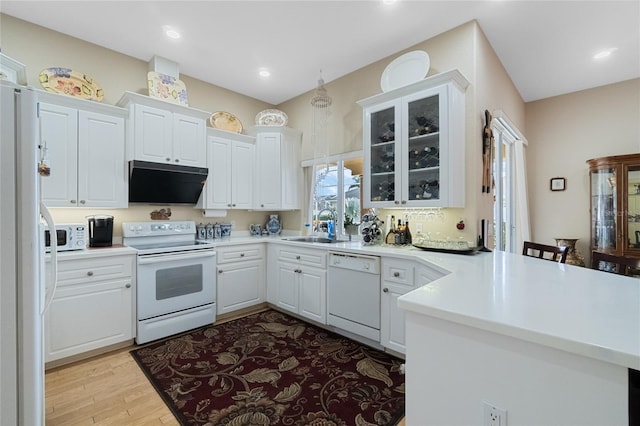 kitchen with white appliances, a sink, white cabinetry, light countertops, and glass insert cabinets