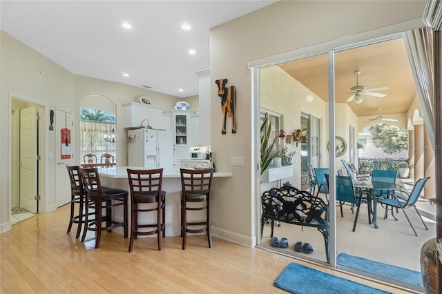 kitchen with white cabinets, glass insert cabinets, a peninsula, light countertops, and white fridge with ice dispenser