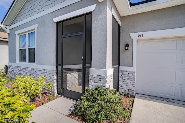 property entrance with a garage, stone siding, and stucco siding